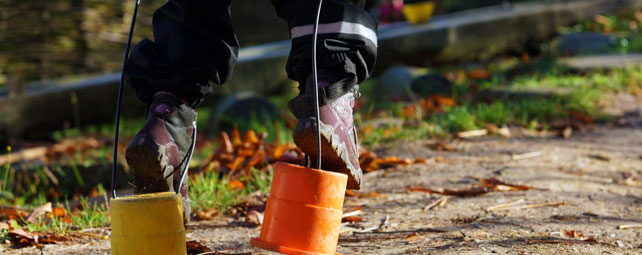 Ein Kind erprobt auf bunten Laufdosen sein Gleichgewicht im Kita-Garten